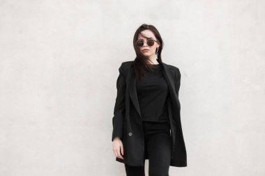 Moda mankeni, havalı ayna gözlüklü, modaya uygun siyah ceketli, modern beyaz duvarın yanında şık bir tişörtü olan muhteşem bir genç kadın. Sokakta moda gençliği kıyafeti giymiş şehirli seksi kız..