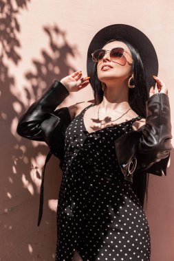 Şapkalı ve güneş gözlüklü siyah elbiseli güzel moda kadını.