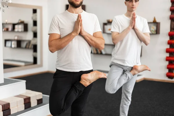 二人の男が一本足で立ち フィットネスクラスで瞑想します 若いです男練習ヨガポーズ — ストック写真