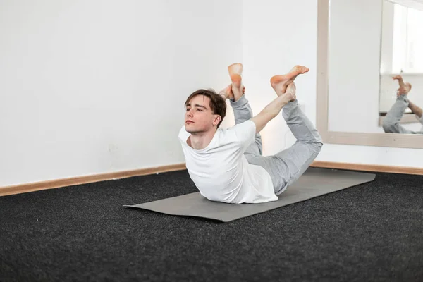白いスポーツウェアの若い男ヨガはフィットネスルームで訓練されています 瞑想と健康の概念 — ストック写真