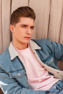 Yakışıklı bir portre, ciddi bir yüz, temiz, sağlıklı bir ten ve şık bir saç stili. Açık havada mavi kot ceketli şık ve çekici bir adam. Erkekler için modaya uygun günlük kot pantolon..