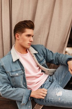 Yeni yaz koleksiyonundan modaya uygun mavi kot pantolonlu yakışıklı genç adam sokakta dinleniyor. Moda kotları giymiş şık bir adam şehirde günlük giysiler giyiyor..