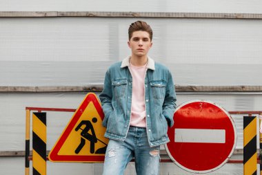 Moda mankeni, modaya uygun mavi kotlu genç adam şehirdeki yeni koleksiyon standından ve yol işaretlerinden giyiniyor. Şık kot elbiseli şehirli adam sokakta yürüyor. Her gün gençliğe bak.