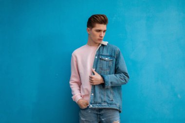 Çok yakışıklı bir genç adam. Şık bir gençlik tarzı var. Sıradan kotlar, göz alıcı güzel pembe kazaklar. Avrupalı moda adamı şehirde manken.