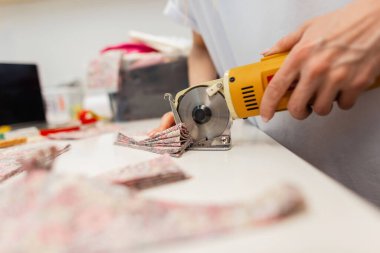 Dikiş imalatında çalışan kadın işçi elektrikli kumaş makinesi kullanıyor. Üretim hattı dikiyorum. Terzi kadın moda tasarımcısı yeni bir kıyafet koleksiyonu yapıyor.