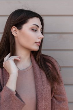 Taze portre çekici, kahverengi saçlı, seksi dudaklı, açık havada klasik ahşap duvarın yanında şık bir palto giyen kadın. Şirin, şık bir manken kız. Güzel, şık bir bayan..