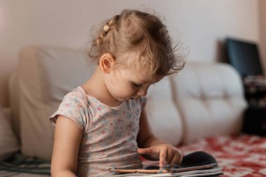 Küçük kız çocuklar evdeki odada bir tabletle ders çalışıp oynuyorlar. İzolasyon ve uzaklık eğitimi