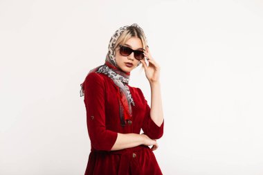Şatafatlı genç kadın model içeride güneş gözlüğünü düzeltiyor. Havalı bir leopar atkısı olan, şık dudakları olan, stüdyoda poz veren seksi sarışın kız. Retro biçimi.