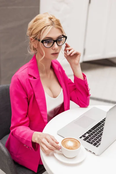 漂亮漂亮的年轻自由撰稿人女士正在互联网上的笔记本电脑上工作 新的金融项目与一杯咖啡在咖啡店 这位女士在办公室里远程办公 — 图库照片