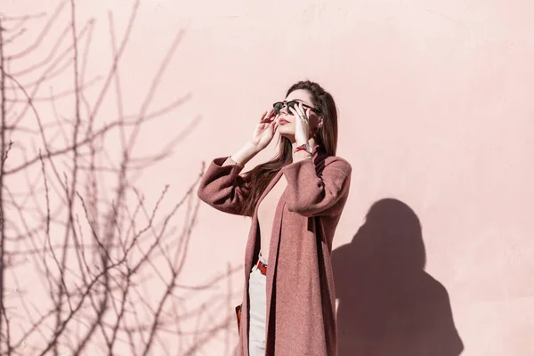 Прекрасная Молодая Женщина Выпрямляет Модные Солнечные Очки Возле Розовой Стены — стоковое фото