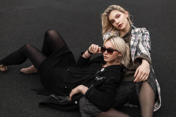 ファッショナブルな服を着た2人の流行の現代の姉妹は 市内のバスケットボールコートで休んでいます スタイリッシュな美しいです女の子ファッションモデルで黒ヴィンテージ着用でサングラスは上にありますセクシー妹でチェッカージャケット — ストック写真