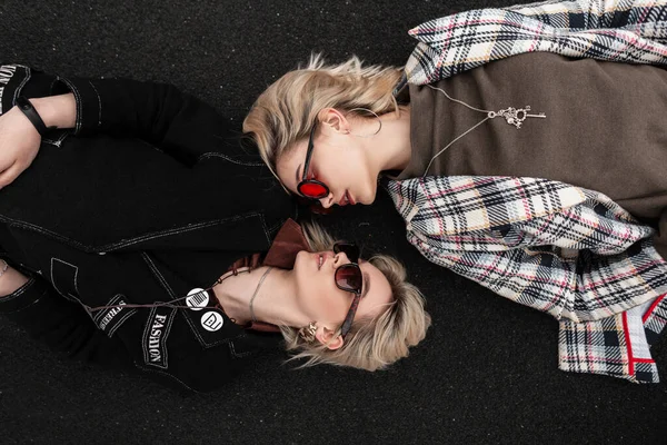 유행하는 선글라스를 고전적 스타일의 매력적 여성들은 아스팔트 위에서 긴장을 서로를바라본다 — 스톡 사진