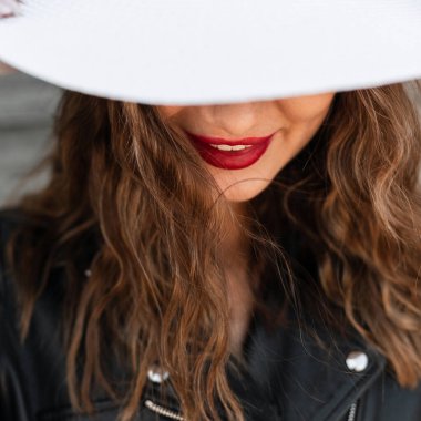 Yakın plan mutlu kadın portresi güzel kırmızı dudakları ve pozitif gülüşü siyah ceketli, siyah saçlı, şapkalı. Zarif şık beyaz şapkalı kadın yüzü..