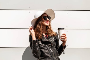 Kahveli, fincanlı gülümseyen kadın portresi ya da siyah ceketli, siyah şapkalı kırmızı rujlu kahve ve sokaktaki duvarın yanında serin güneş gözlüğü..