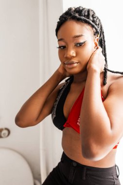 Havalı, şık, kırmızı-siyah bandanalı saçı olan, pencerenin yanında poz veren Afro-Amerikalı güzel bir kadın. Çekici, seksi afro kız model..