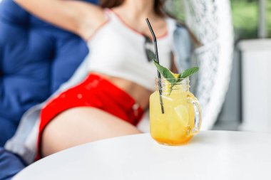 Kafedeki masada buzlu ve naneli taze sarı limonata var. Kadınlar yaz terasında rahatlar ve sıcak yaz gününde güzel bir içki içerler..