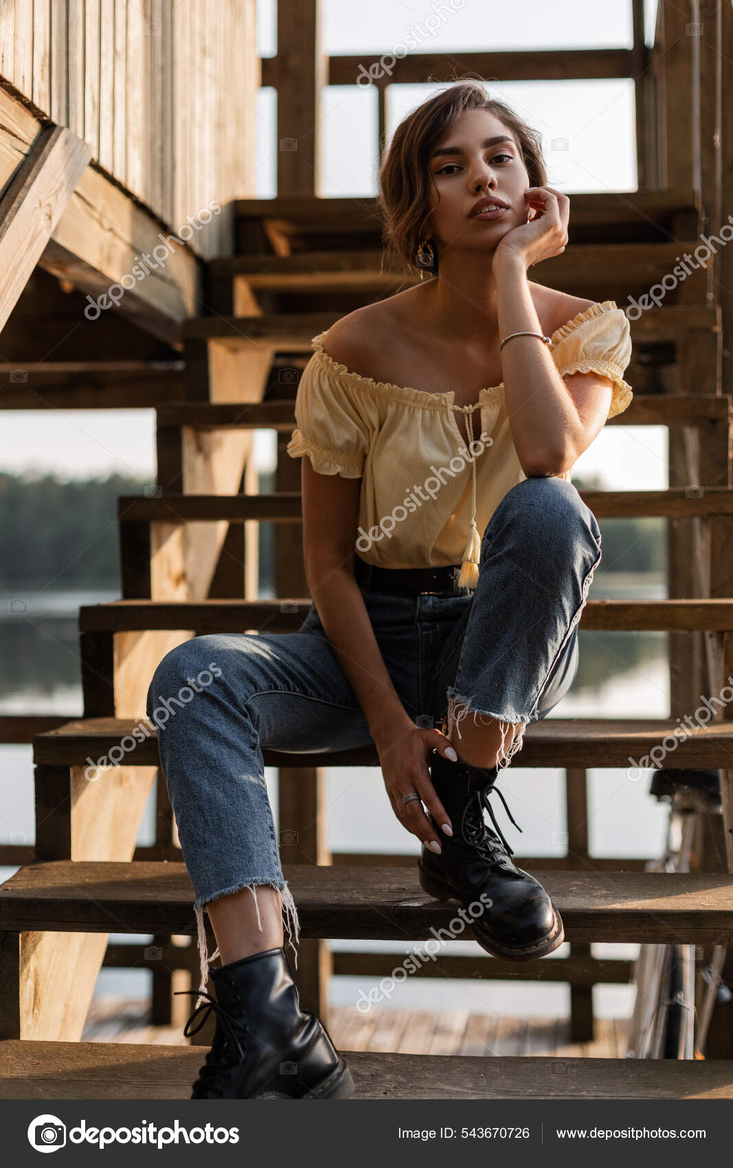 Fashion model with curly hairstyle and glamour make-up wearing cropped top  and ripped jeans posing outdoor. Positive emotions. Stock Photo | Adobe  Stock