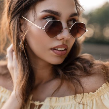 Yazın moda güneş gözlüklü güzel, kıvırcık bir kadının moda portresi. Dişi güzel yüz