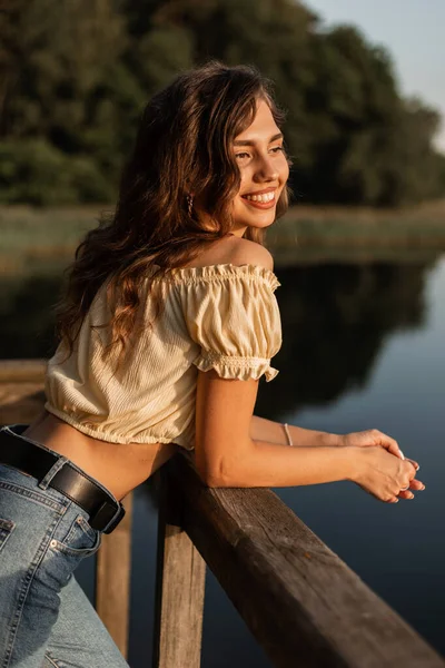 面白いです可愛いです女性モデルでかわいい笑顔でファッション夏服は日没時に湖の近くに自然の中で休んで — ストック写真