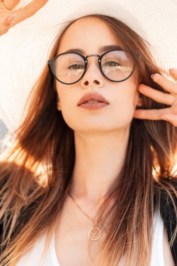 Güzel Vogue portresi, genç ve güzel bir kadın, genç dudakları, siyah gözlüklü, parlak güneşli bir günde zarif şapkalı seksi bir kadın. Moda mankeni, yaz güneşinin sıcacık ışınlarından zevk alır..