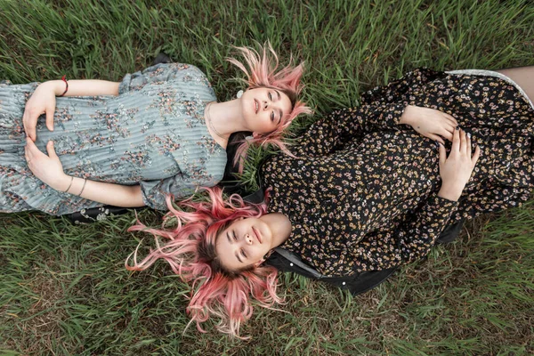穿着时髦夏装的金发美女们躺在城外田野里鲜绿的草地上 穿着青春夏装的漂亮女孩们周末都喜欢躺在草地上晒太阳 — 图库照片