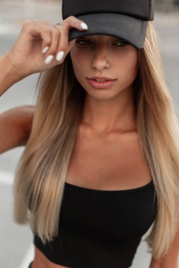 Siyah elbiseli genç, güzel hippi kadın sokakta siyah şapkasını düzeltiyor, yakın plan.