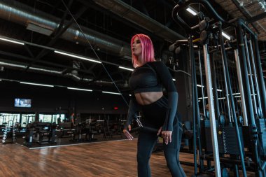 Spor salonunda spor kıyafetli, şık bir kadın spor salonunda çalışıyor.