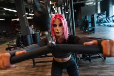 Spor salonunda çalışan siyah eşofmanlı güzel genç bir kızın dinamik fotoğrafı.