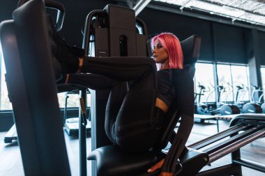 Güzel ve sportif bir kadın spor salonunda bacak kaslarını çalıştırmak için egzersiz yapıyor.