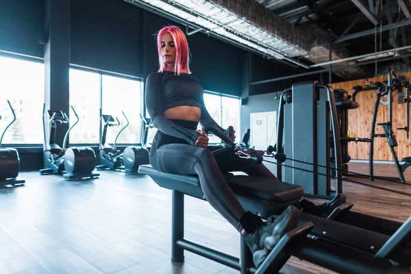 Sportif, şık, siyah spor kıyafetli genç bir kadın spor salonunda spor yapıyor ve egzersiz yapıyor.