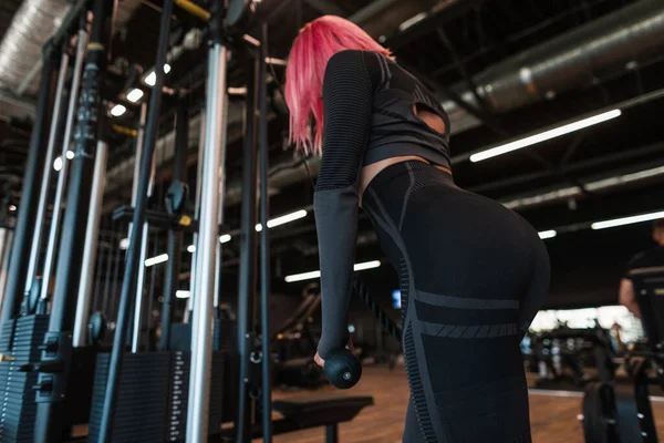 黒スタイリッシュなスポーツウェアで健康的なフィットネスモデルの女性が動作し トレーニング機器の筋肉をポンプ サイドビュー — ストック写真