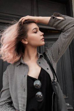 Moda kıyafetleri içinde pembe saçlı, klasik ekose gömlekli ve sokakta siyah tişörtlü güzel bir kadının yeni moda portresi.