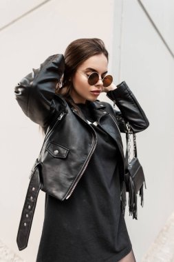 Siyah rock tarzında, gri arka planda şık güneş gözlüklü güzel bir kadının moda şehir portresi. Güzellik ve Gelişigüzel Kadın Biçimi