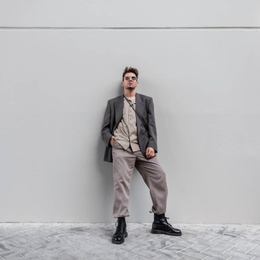 Şık giyinmiş şık genç hippi şehirde gri duvarda gömleği, ceketi ve çizmeleri var.