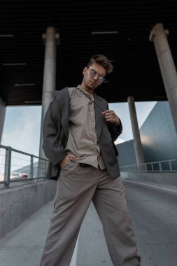 Moda gözlüklü, şık gri takım elbiseli, şık, genç ve yakışıklı bir adam.