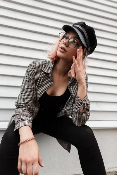 안경을 아름다운 모델이 평범하게 유행하는 셔츠를 모자를 나무집 근처에 — 스톡 사진