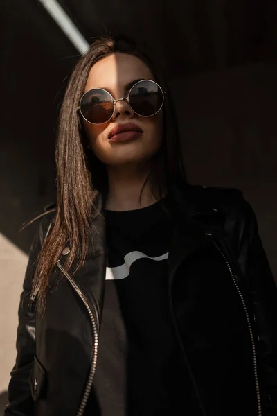 Mujer Joven Hipster De Moda Con Gafas De Sol De Moda Con Ropa Juvenil  Elegante Endereza La Gorra Negra Americana En Un Día Soleado En El  Estacionamiento. Chica Modelo Urbana Posando Al