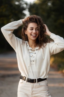 Mutlu kıvırcık kız, güzel bir gülüşü, dişleri ve doğa üzerine örülmüş bir bluzu var. Güzel bir kadın yüzü