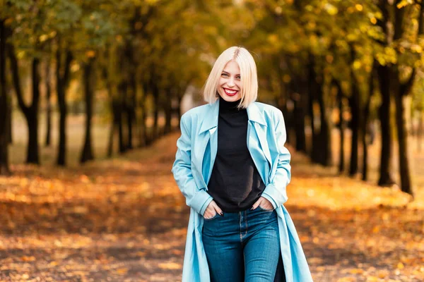 공원에서 코트와 스웨터와 청바지를 유행하는 귀여운 미소를 행복해 여성의 스타일 — 스톡 사진