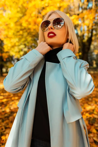 紅葉の美しい秋の公園でヴィンテージサングラスとファッションブルーのコートで赤い唇を持つ美しい若い女性の肖像画 — ストック写真