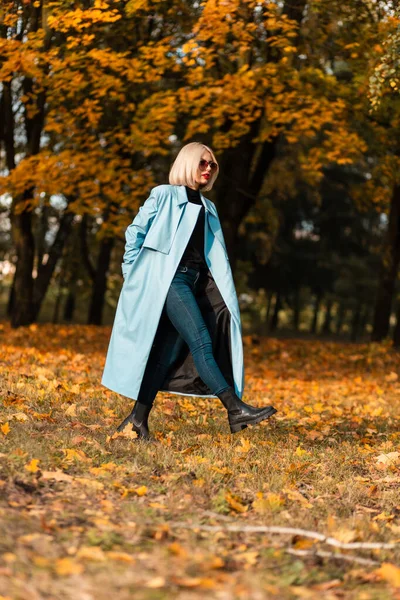 穿着时髦蓝色外套的时尚优雅的金发女模特走在一个金光闪闪的迷人的秋天公园里 — 图库照片