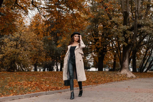 黄色の紅葉の木々の近くの公園でファッションバッグウォークと流行の灰色のコートの帽子を持つファッショナブルな美しい女の子モデル — ストック写真