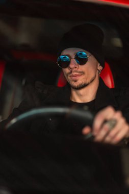 Mavi güneş gözlüklü ve şapkalı yakışıklı hippi direksiyonun arkasında oturuyor. Trip ve yolculuk