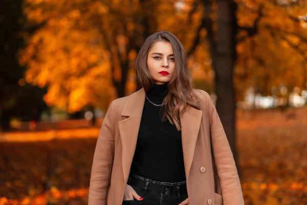 穿着时髦的米黄色古装 头戴毛衣 红唇的漂亮姑娘 走在一个长着橘红色叶子的秋天公园里 — 图库照片