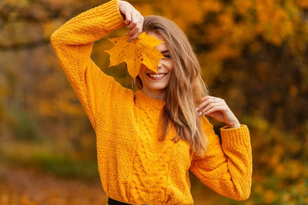 快乐的年轻微笑的女人穿着黄色的老式针织毛衣 满脸金黄的秋叶 在户外享受着五彩缤纷的落叶 时尚女性风格与美 — 图库照片