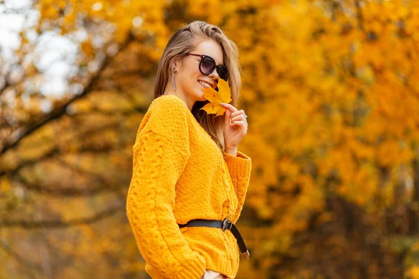 快乐美丽的小女孩 穿着时髦的针织黄色毛衣 带着淡淡的秋叶 有着淡黄的落叶 — 图库照片