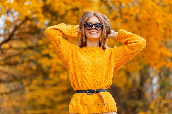 스웨터를 두르고 황금빛 잎사귀로 가을을 즐기는 선글라스를 이미소짓는 이있다 — 스톡 사진