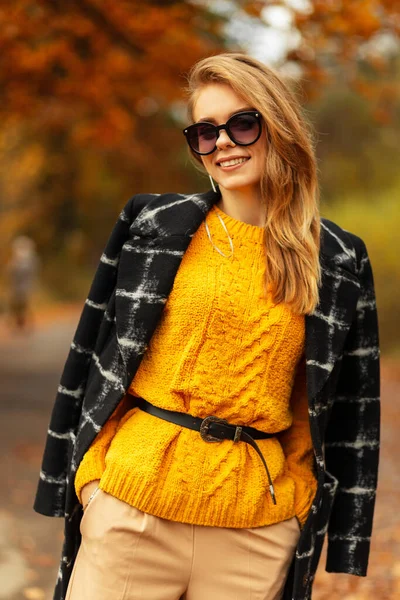 Szczęśliwa Młoda Kobieta Uśmiechem Okularach Przeciwsłonecznych Stylowym Płaszczu Żółtym Swetrem — Zdjęcie stockowe