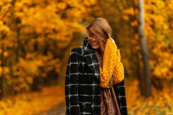 快乐的漂亮微笑的女人 穿着时髦的衣服 黑色外套和黄色针织毛衣 在迷人的金碧辉煌的公园里享受秋天的天气 — 图库照片