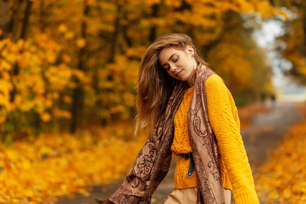 穿着老式针织黄色毛衣 头戴围巾 快乐的年轻漂亮的女人 走在公园里 绿叶飘扬 秋天的黄叶飘扬 — 图库照片